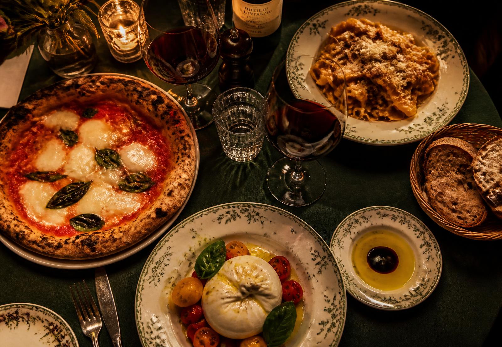 Italian table spread with wood-fired pizza, pasta and burrata